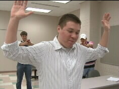 Students draw guns in a mock IRS arrest of a 'tax cheat'.